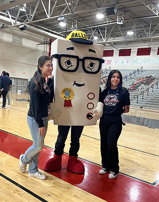 two students next to someone dressed up as a ballot