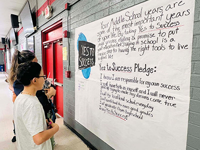 Students reading a sign about Yes to Success