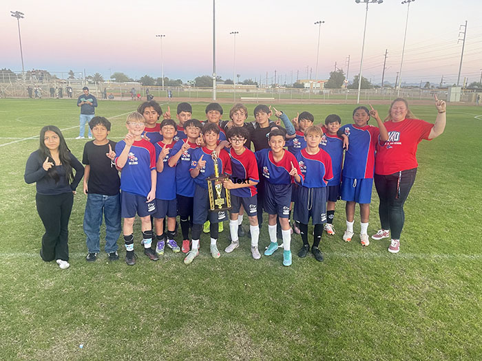 Boys soccer team holding up a big trophy