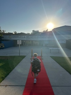 Student wearing a backpack walking toward the school building on the first day of school