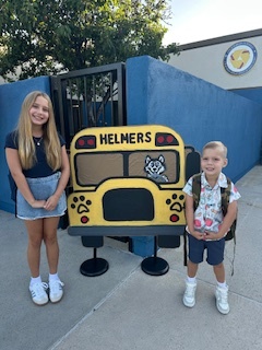 Two students next to a Helmers bus poster