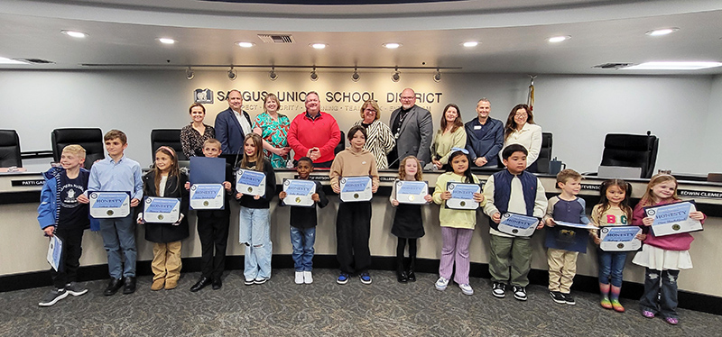 Group of happy students being recognized for honesty at a board meeting