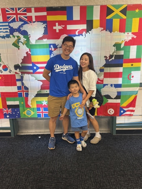 Family smiling for a picture in front of a map of the world
