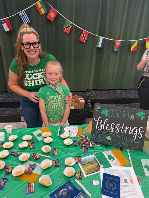 Woman and school girl dressed in green behind an Irish table