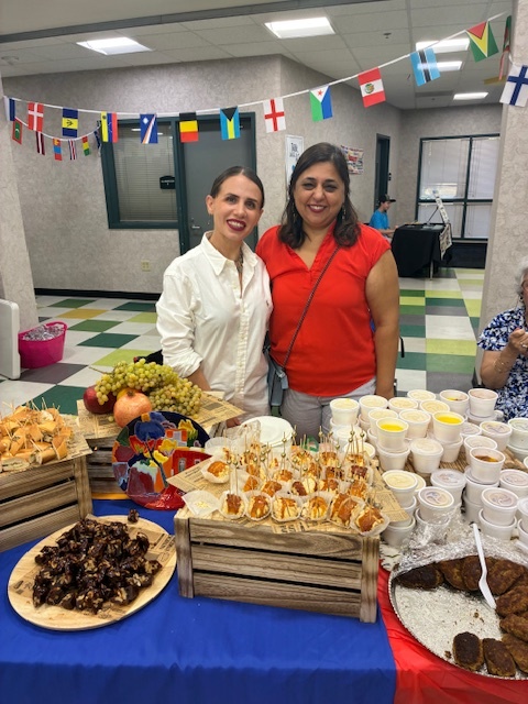 Two women smiling behind a beautiful food table