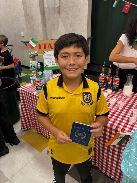 School boy in yellow soccer shirt holding up a passport