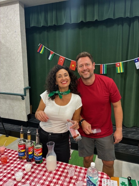 Two happy adults manning a table at the Multicultural Event at North Park Elementary
