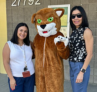 Two teachers posing with the Cedarcreek mascot