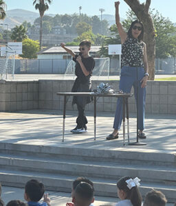 Teacher and student with a microphone cheering for young students