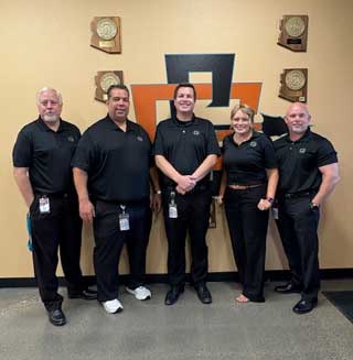 Staff member in front of Aztec sign on the wall