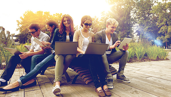 High School students enjoying the summer weather outside while learning on their laptops and tablets