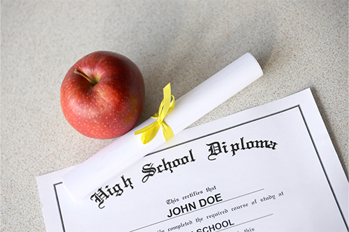 High school-diploma-lies-table-with-small-scroll-red-apple