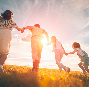 A family of four holding hands while outside on a hillside