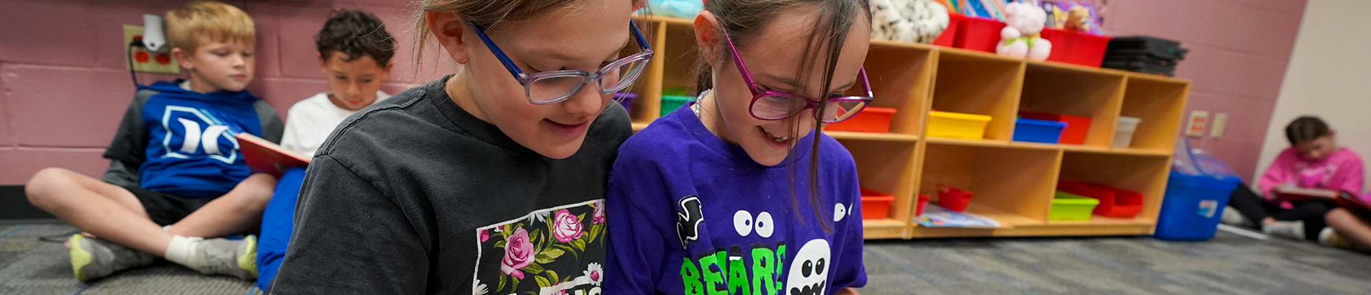 Two elementary girls reading together