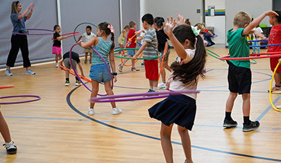 Students in the gym exercising with hula hoops