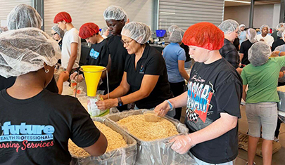 Crismon High School students in a kitchen helping to prepare meals to donate to local food banks
