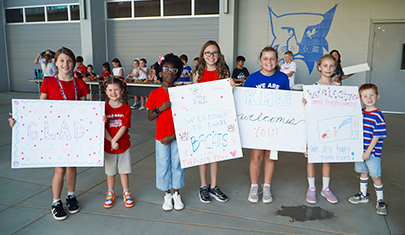 Happy students holding up posters outside