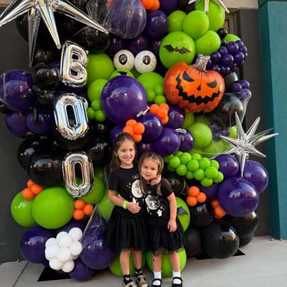 Two students in front of a display of Halloween balloons.