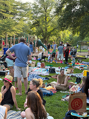 Family members sitting on the ground or standing visiting with each other at the end-of-the-year picnic