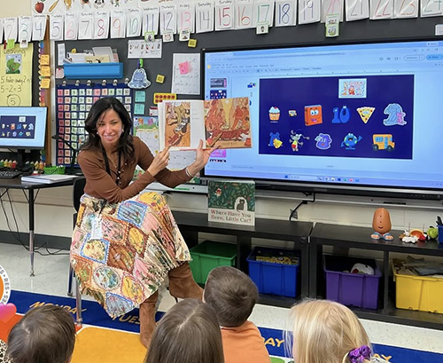 Dr. Susie Da Silva reading a book to school children