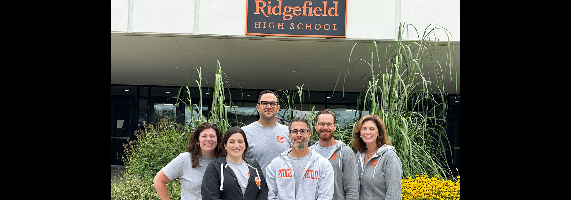 Happy staff members under the Ridgefield High School sign
