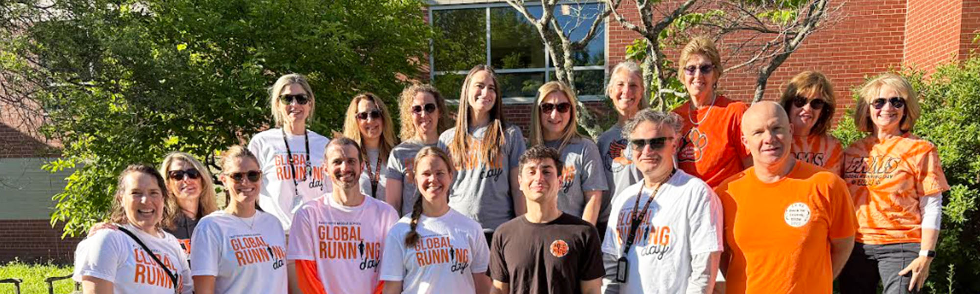 Group of happy staff members posing for a picture outside for Global Running Day