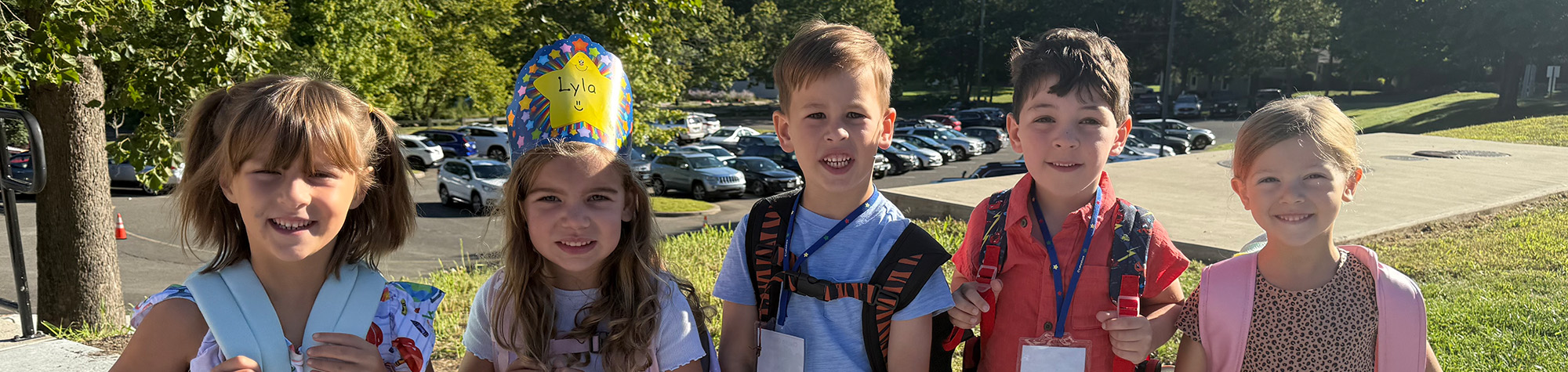 students with backpacks and one with a paper crown