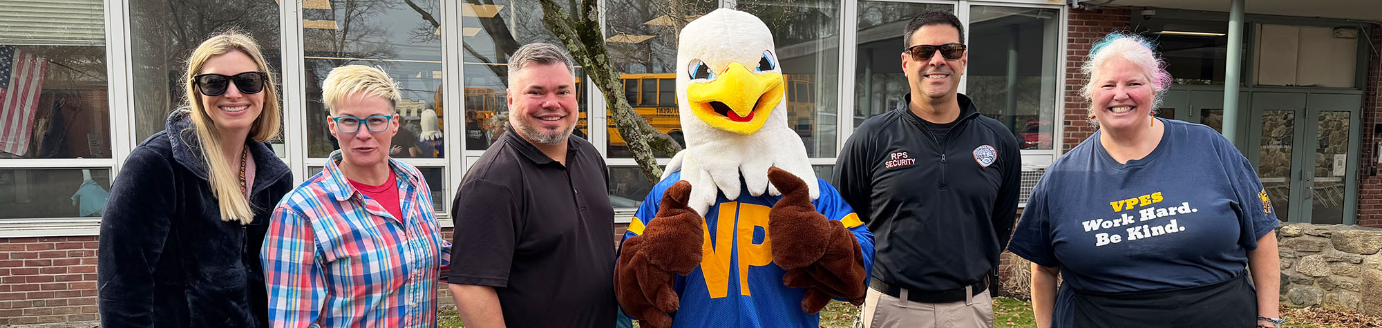 Group of happy staff members outside with school eagle mascot