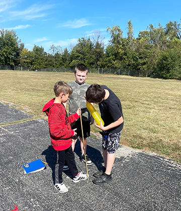 Three boys outside working on a balloon science project