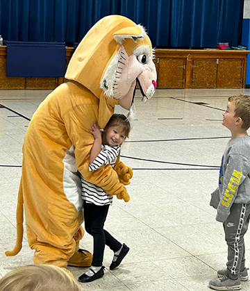 School mascot giving a hug to a elementary school girl