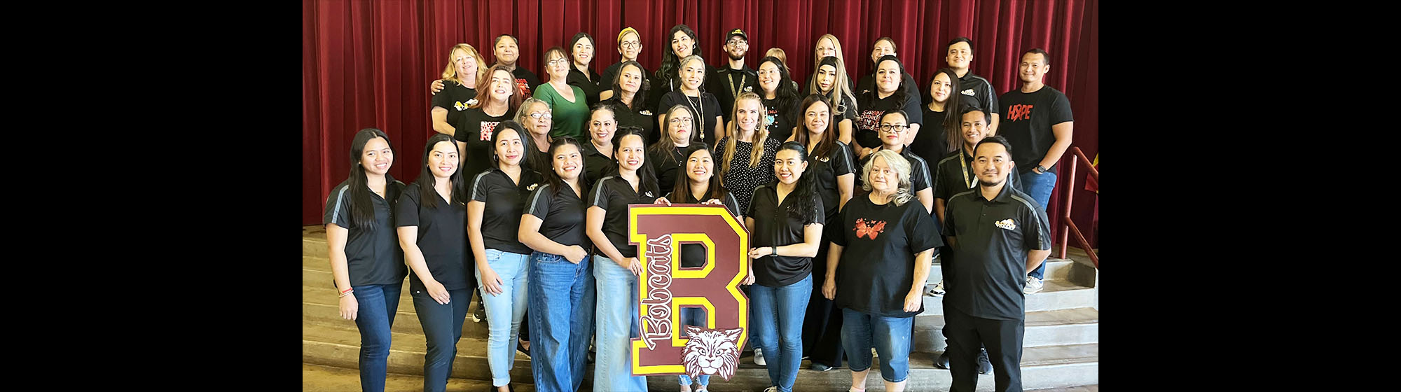 Staff members posing for a photo and holding up a big letter B for Bobcats