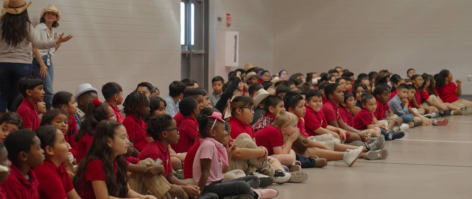 students sitting on the floor in the gym