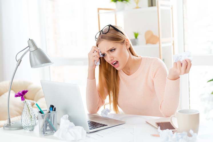 Portrait of angry annoyed girl having problem with laptop having crumpled papers