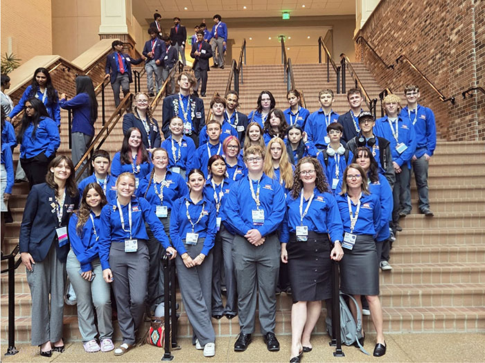 Group of students in bright blue shirts attending a conference