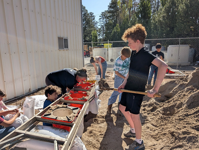 Students working with shovels and dirt on an outside project
