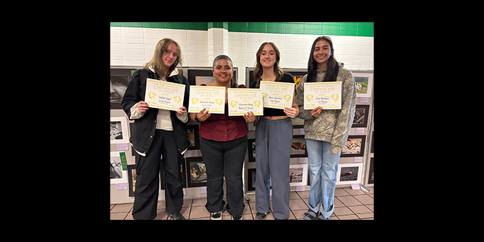 Four students holding up art show certificates for their artwork