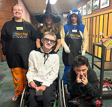 Group of happy students with teacher in hallway
