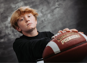 student holding out a football