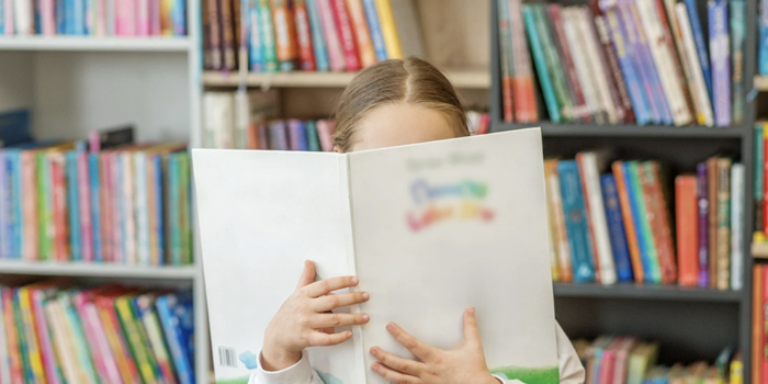 Elementary student holding up a library book in the library