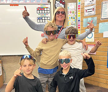 Group of happy second grade students with Mrs. Vallverdu wearing sunglasses