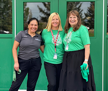 Three happy staff members dressed up for Green Day at school