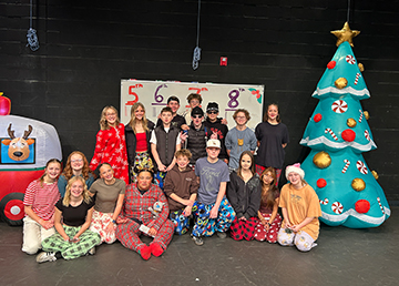 Group of students posing for a picture on a Christmas decorated stage