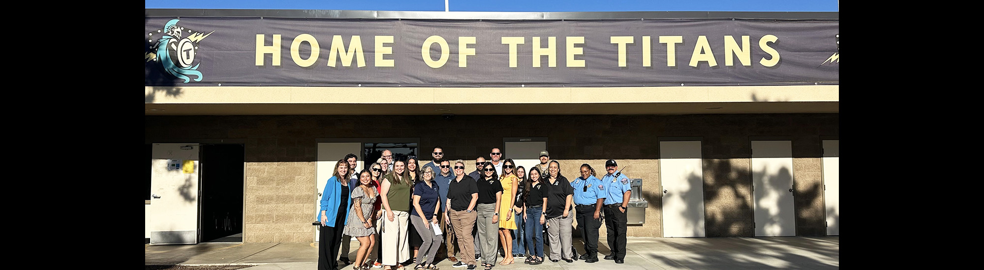 Happy staff members under the Home of the Titans