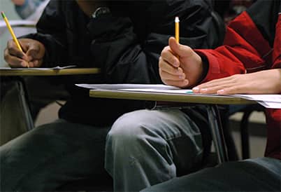 2 students sitting at a desk with a pencil in hand