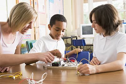 Teacher and students working on a circuit board Teacher and students working on a circuit board