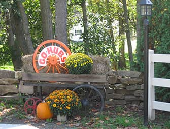 A cart with hay, flowers, pumpkins and a sign that reads Go-Hubs