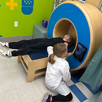 students acting as a patient and a doctor at a MRI looking display