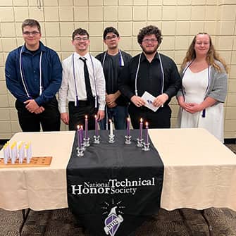 students standing behind a table with candles the reads National Technical Honor Society