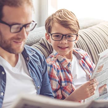 Boy reading newspaper with father