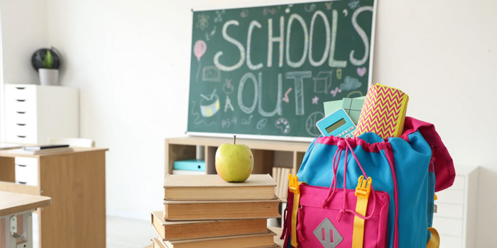 Schools Out board in a classroom with a colorful backpack